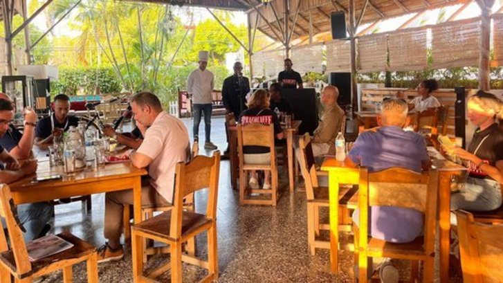 Wide view of the rustic wooden indoor terrace at Fellini Restaurant in Miramar, Playa, with guests dining at wooden tables under natural light.