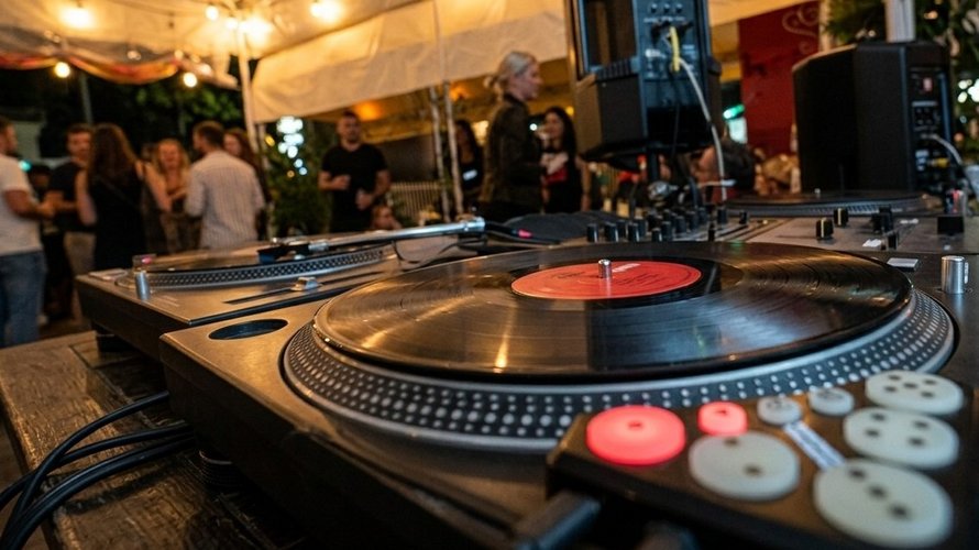 Close-up of a professional DJ turntable and controller with glowing red buttons during a night event at Fellini in Miramar.